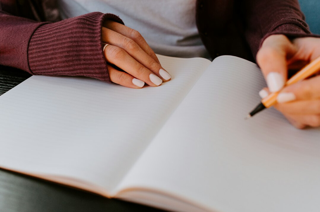 woman writing at desk with notebook